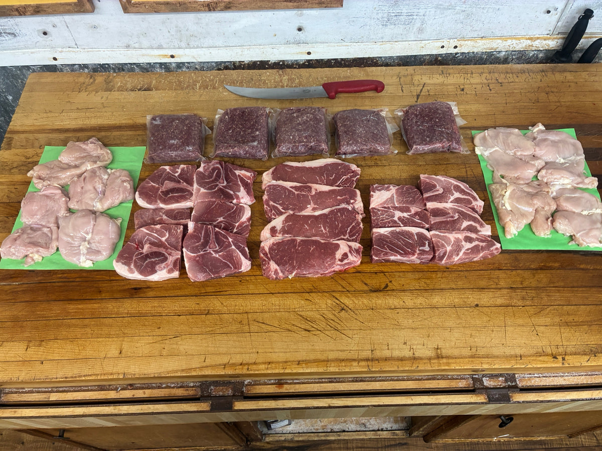 The Deep Freeze box — ground beef, pork steaks, strip steaks and boneless skinless chicken thighs laid out on the butcher block at Country Meat Market