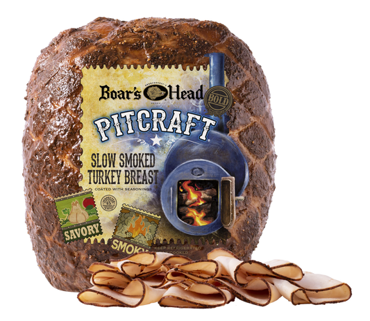 Boar's Head Pitcraft slow smoked turkey breast, shown as a large browned cube with a printed front label and several sliced pieces arranged in front on a white background.