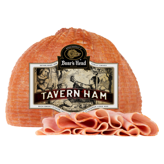 Boar's Head Tavern Ham in the package with a sliced pile of ham slices in front, on a plain white background.