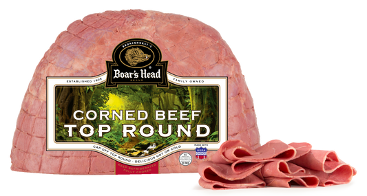 Boar's Head Corned Beef Top Round in its branded vacuum packaging, with several slices cut from the front resting on a white background.